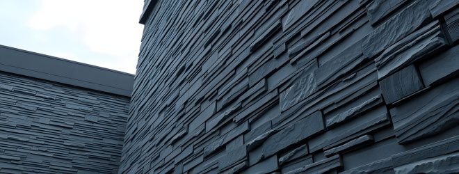 Close-up view of modern building exterior with textured, rectangular stone cladding in various sizes and shades of grey.